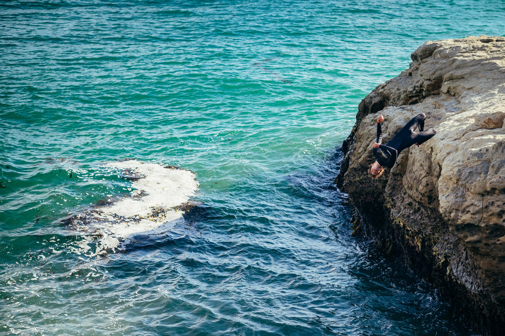 Surfer does a backflip cliff jump