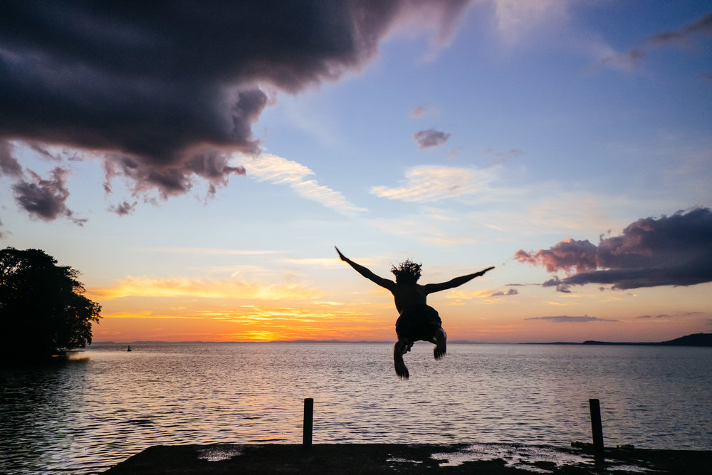 Young boy jumps off a dock at sunset on Ometepe Island